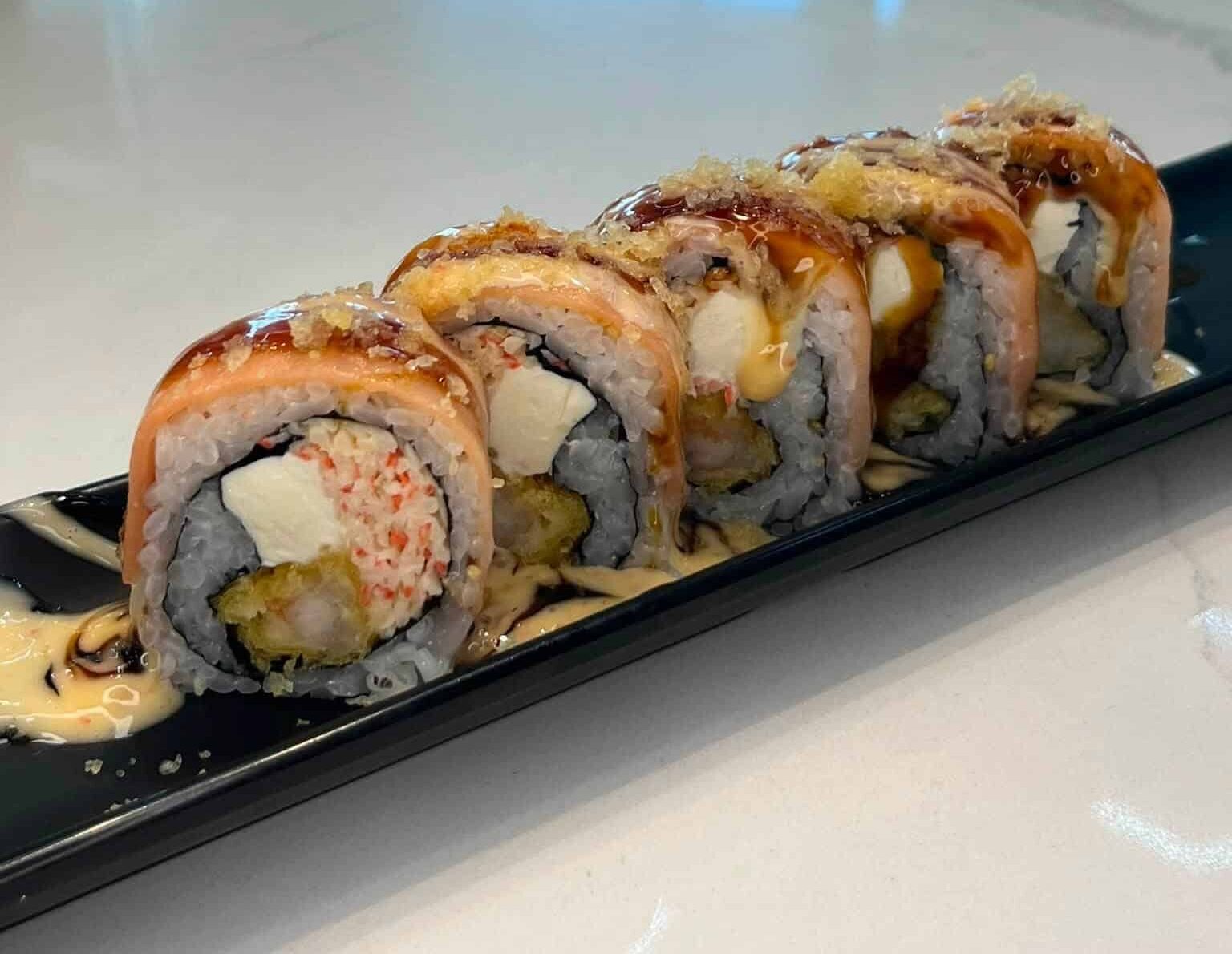 Five pieces of a sushi roll on a black plate